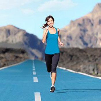 Une jeune femme souriant fait un jogging sur une route
