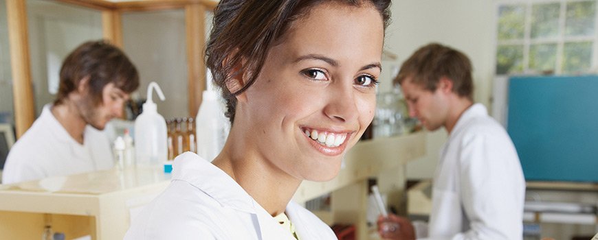 Une jeune femme souriante travaillant dans le laboratoire de recherche de Dr. Schutz